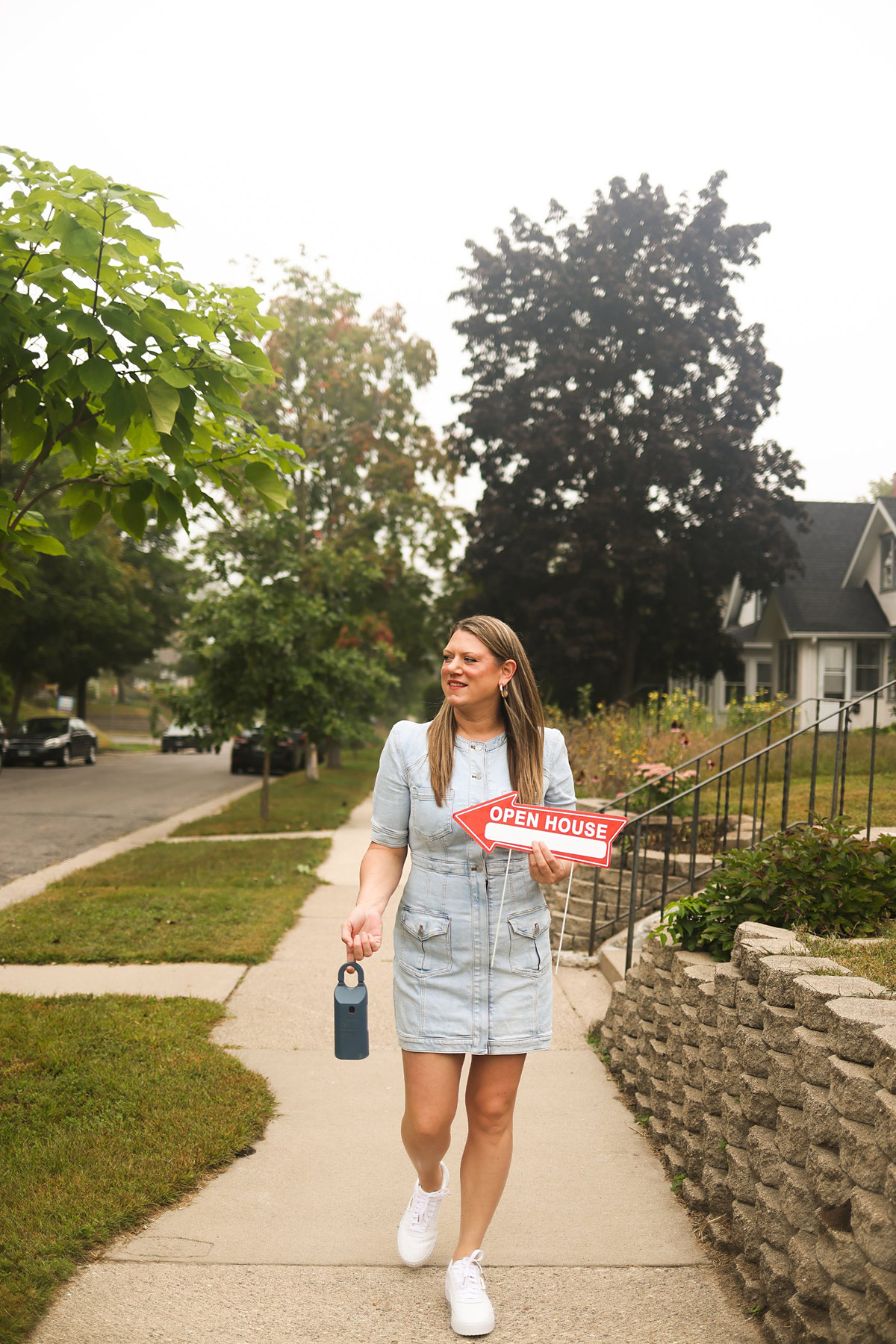 Candice walking a Twin Cities sidewalk with an open house sign